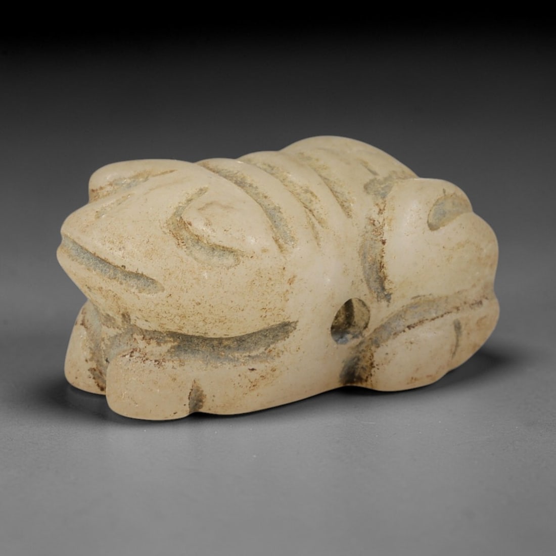 Ancient Chalcedony Frog Amulet - Egyptian Figurine, 75AR: This artifact is carved from pale, milky-white chalcedony, exhibiting a smooth, polished surface with subtle natural inclusions and faint surface wear consistent with age. The form is a stylized frog