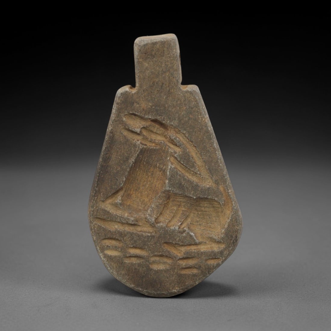 Ancient Schist Amulet Pendant - Near Eastern Animal Figurine, 30ZQ: Carved from schist, this pendant features a stylized animal motif with incised detailing on one face and a grid of small circular depressions on the reverse. The stone has a muted earth-toned patina w