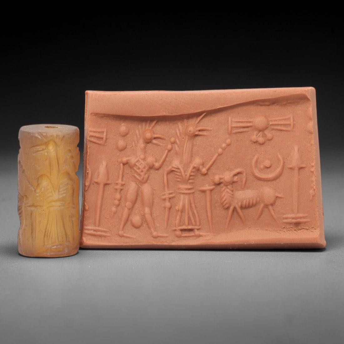 Ancient Small Chalcedony Cylinder Seal - Mesopotamian Avian & Ritual Scene, 75ZS: Carved from warm-hued chalcedony, this diminutive ancient Mesopotamian cylinder seal features an intricate linear relief composition of two avian-headed ritual figures flanking a caprine creature, pun