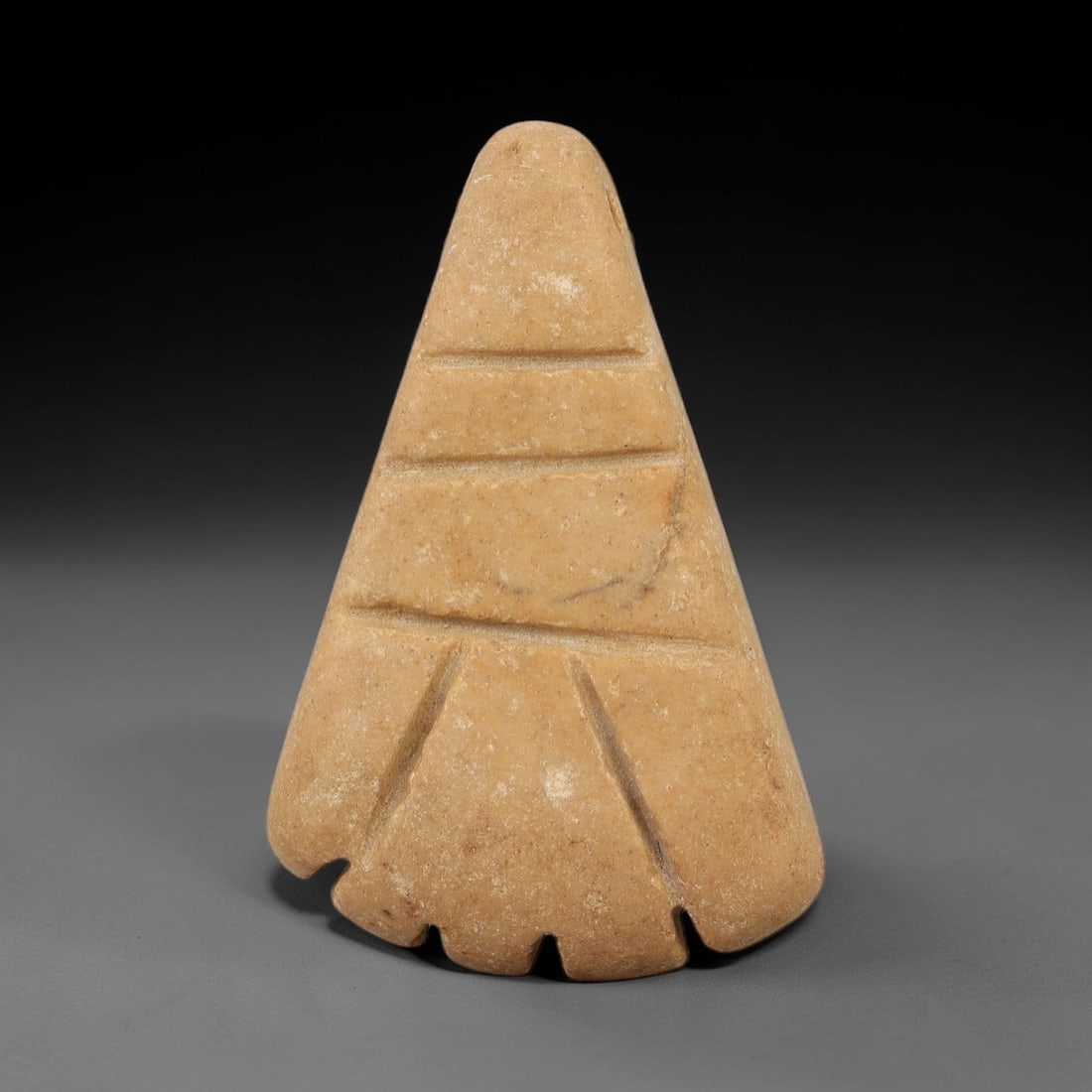 Ancient Stone Palm Amulet - Near Eastern Pendant, 35AE: This artifact is a carved stone palm amulet of Near Eastern origin, fashioned from a warm, ochre-toned stone with a fine, granular texture. Its triangular form tapers to a rounded apex with a drilled