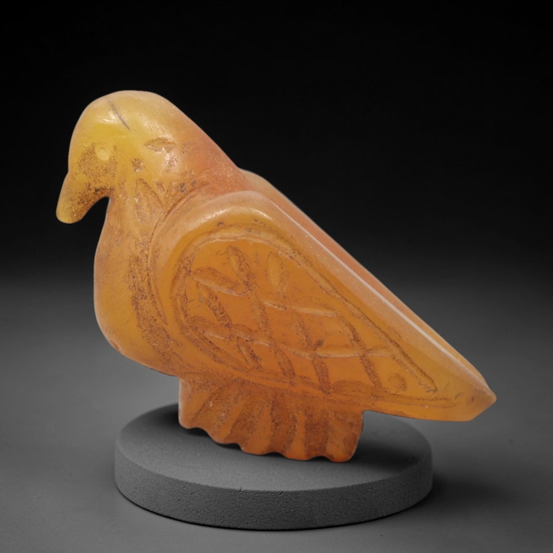 Ancient Carnelian Bird - Near Eastern Figurine, 25XV: This artifact is a carved carnelian bird, featuring a stylized avian form with incised geometric and linear patterns across the wing and body, consistent with Near Eastern decorative iconography. The
