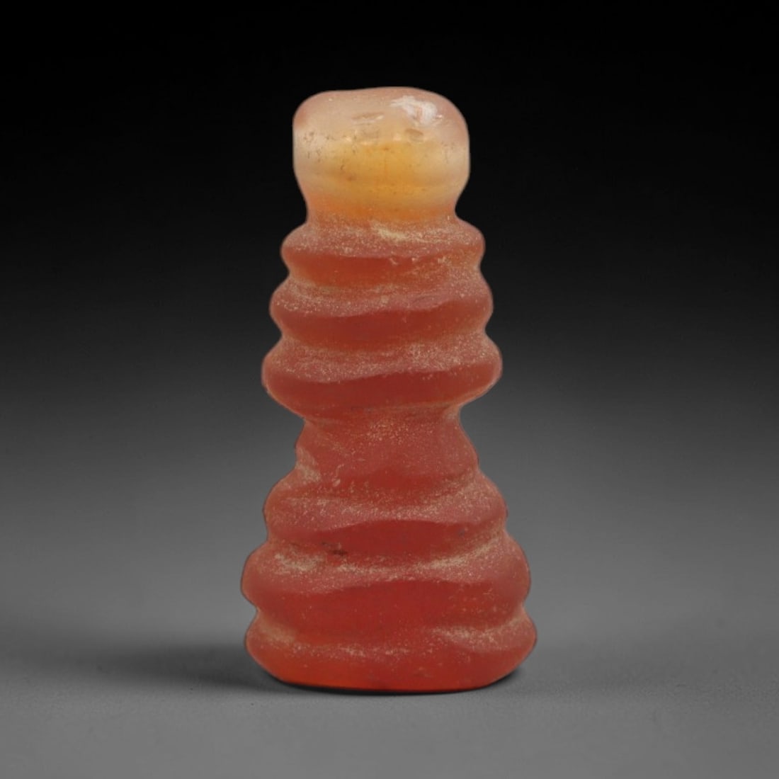 Ancient Agate Djed Pillar - Egyptian Amulet Bead, 94XS: This amulet is carved from translucent orange-red agate, exhibiting natural banding and a warm, glossy finish characteristic of ancient Egyptian glyptic craftsmanship. The form is a Djed pillar, a sac