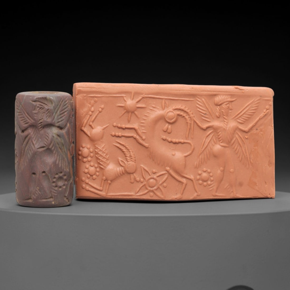 Ancient Steatite Cylinder Seal - Mesopotamian Winged Deity & Animal Scene, 38AL: Carved from rich, variegated steatite, this ancient Mesopotamian cylinder seal depicts a detailed mythological scene, executed with meticulous glyptic craftsmanship characteristic of the Late Bronze A