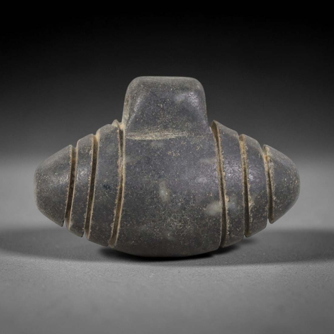 Ancient Stone Segmented Amulet - Near Eastern Pendant, 61AR: This artifact is carved from a dark, granular stone with a smooth, matte finish and subtle surface wear consistent with age. The form is a symmetrical, bulbous amulet with a raised rectangular top lug