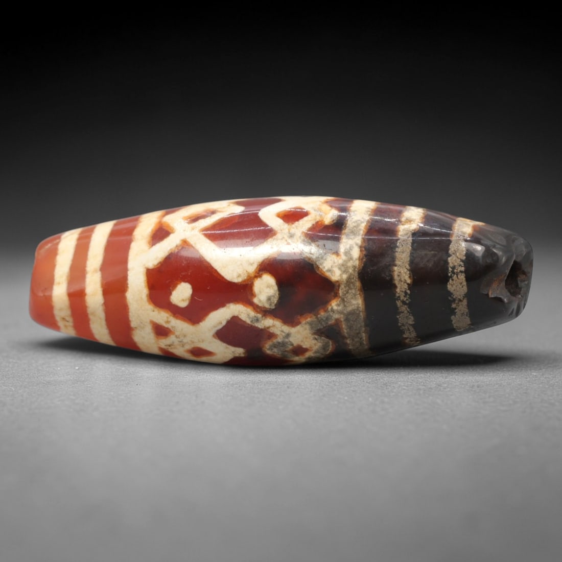 Ancient Carnelian Etched Dzi Bead - Himalayan Amulet, 80XV: Crafted from rich banded carnelian, this bead features intricate etched white geometric and symbolic motifs, flanked by parallel linear bands, executed in the traditional Himalayan Dzi bead technique.