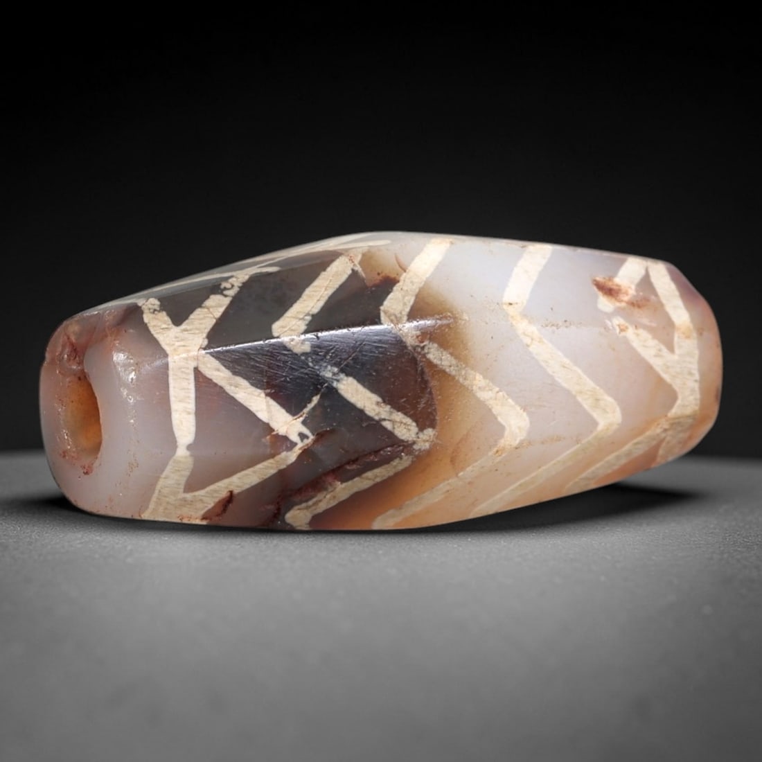 Ancient Agate Dzi Bead - Himalayan Chevron Amulet, 11AS: This ancient elongated bead is crafted from polished banded agate, featuring a pale pinkish-brown base with crisp white etched chevron motifs across its multi-faceted surface. The bead retains a fine,
