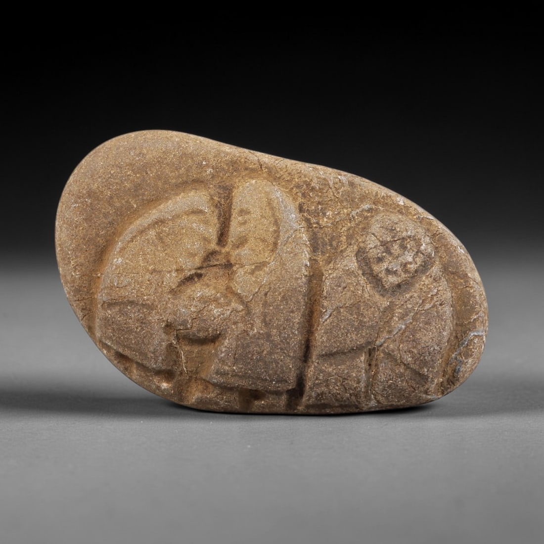 Ancient Stone Figural Amulet - Near Eastern Christian Trio, 98FX: Carved from a naturally smoothed river stone, this piece features a bas-relief depiction of three standing figures, likely representing a Christian holy trio or devotional group, with incised lines de