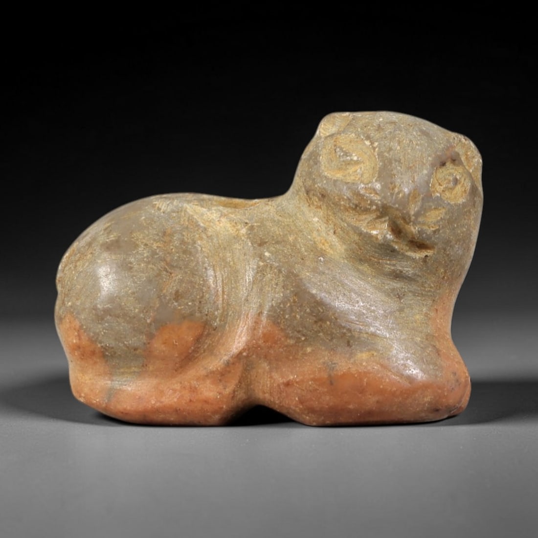 Ancient Stone Feline - Near Eastern Amulet Figurine, 39AS: This amulet is carved from variegated stone, displaying a two-toned earthy patina consistent with ancient Near Eastern burial contexts. The form depicts a recumbent feline, rendered in a compact, styl