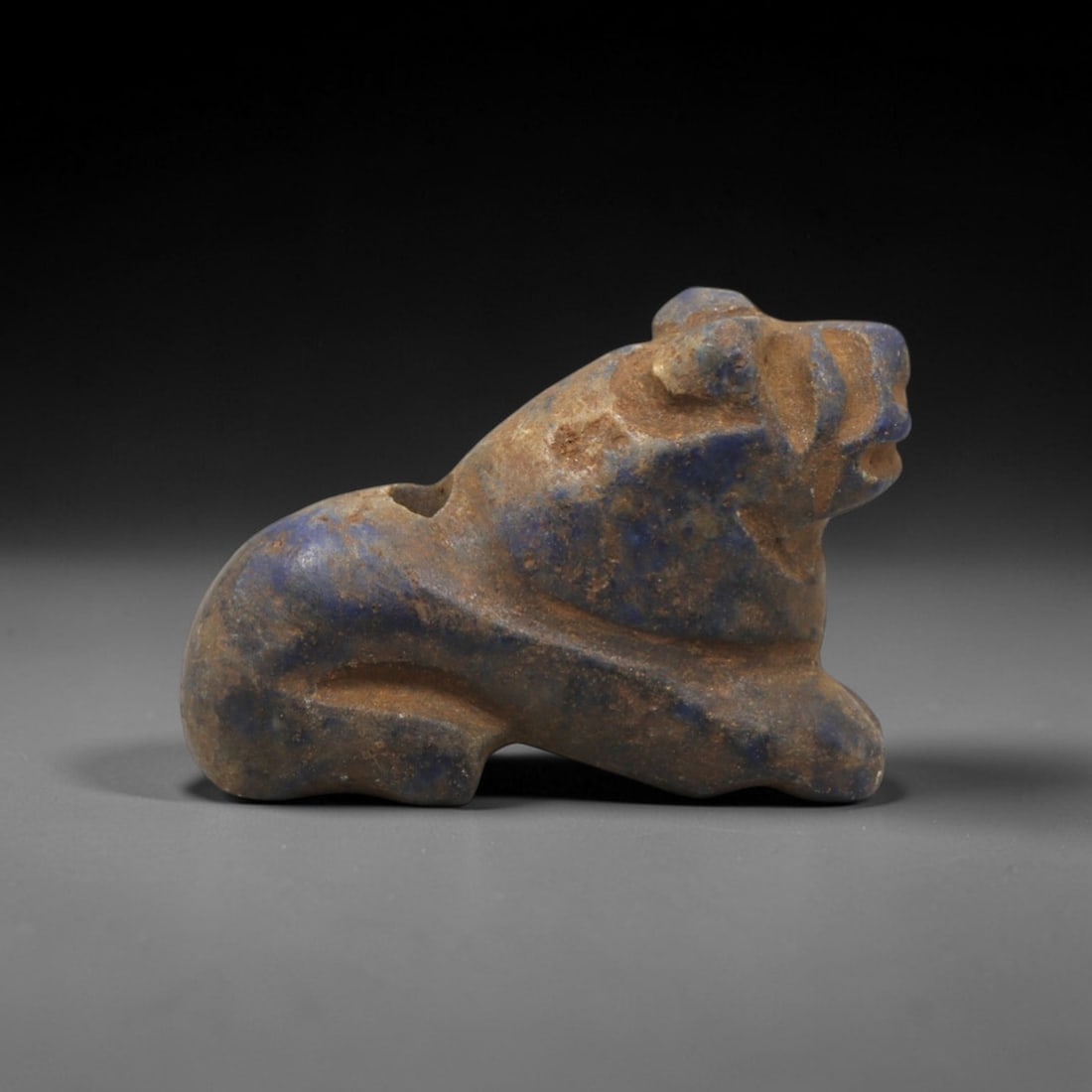 Ancient Lapis Lazuli Lion - Near Eastern Amulet Figurine, 2XT: Carved from lapis lazuli, this amulet depicts a recumbent lion in a stylized, rounded form. The head is raised with incised facial detailing, a defined snout, and small rounded ears, while the body is