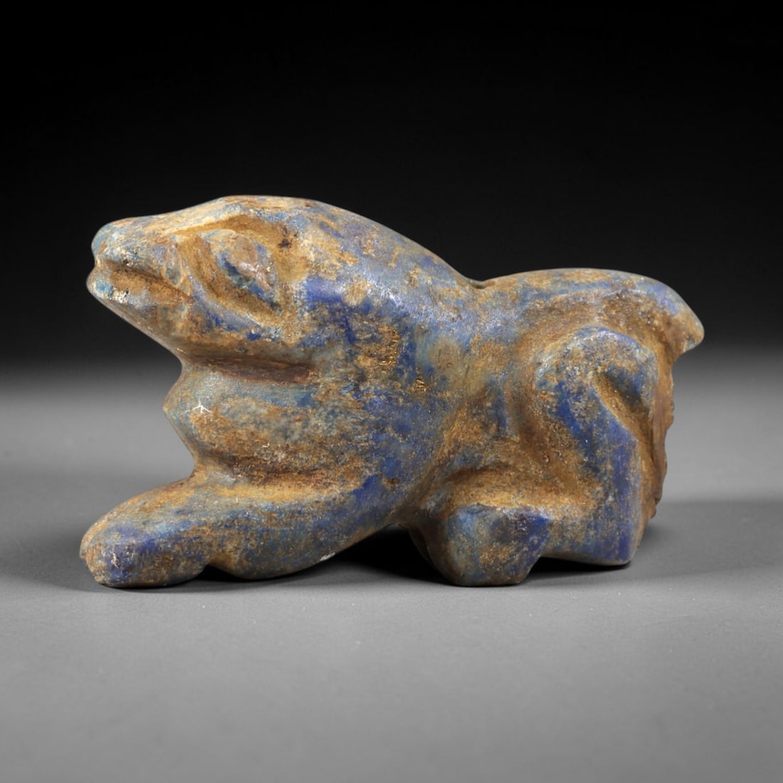 Ancient Lapis Lazuli Feline - Near Eastern Amulet Figurine, 36AS: Carved from lapis lazuli, this amulet depicts a recumbent feline form with stylized facial features and a streamlined, crouched body. The head is forward-facing, with incised eyes, a defined snout, an