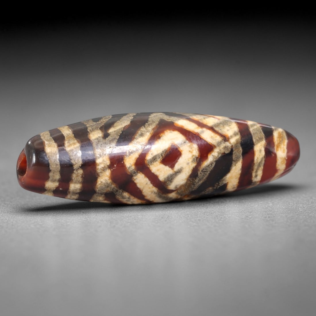 Ancient Agate Dzi Bead - Himalayan Etched Pendant, 12AS: This ancient etched bead is crafted from polished agate, featuring a rich carnelian-hued base with contrasting white etched geometric motifs, including a central diamond motif flanked by linear