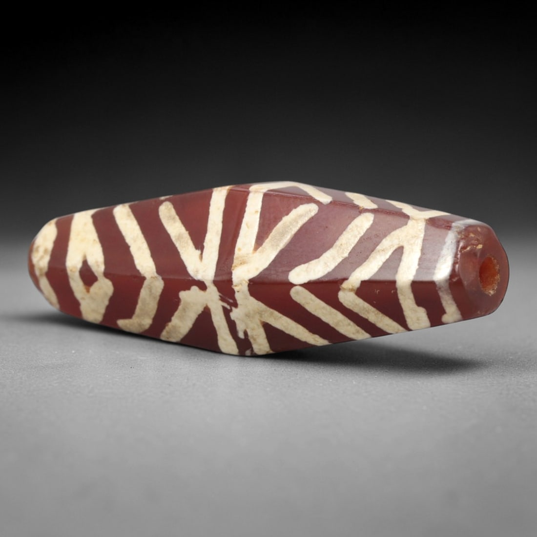 Ancient Carnelian Etched Dzi Bead - Himalayan Amulet, 66XV: Crafted from rich translucent carnelian, this faceted bead features bold etched white radiating linear and geometric motifs, executed in the traditional Himalayan Dzi bead technique. The form is an el