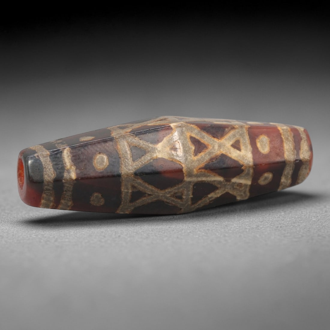 Ancient Agate Etched Dzi Bead - Himalayan Amulet, 67XV: Crafted from dark banded agate, this bead displays elaborate etched geometric patterns, including interlocking stylized 'X' or star motifs, flanked by linear bands and dot inclusions, executed in the