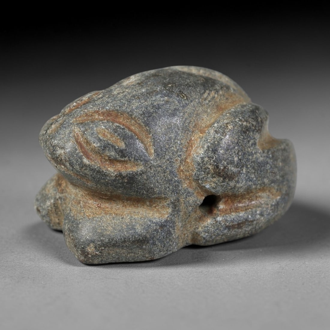 Ancient Stone Zoomorphic Frog - Egyptian Amulet Figurine, 29AS: Carved from speckled hardstone, this amulet depicts a compact, crouched zoomorphic frog form with stylized facial features. The head is broad with incised eye and mouth detailing, while the body is ro