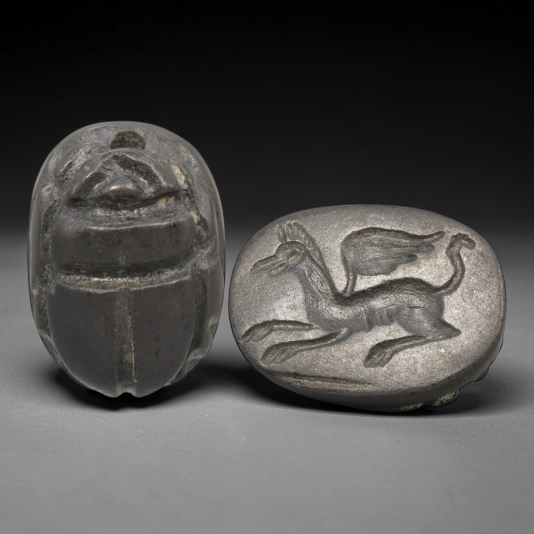 Ancient Hardstone Scarab - Near Eastern Griffin Seal, 20XT: This artifact is hand-carved from a dark hardstone, utilizing traditional ancient seal craftsmanship consistent with Near Eastern or Phoenician traditions. The object takes the form of a scarab beetle