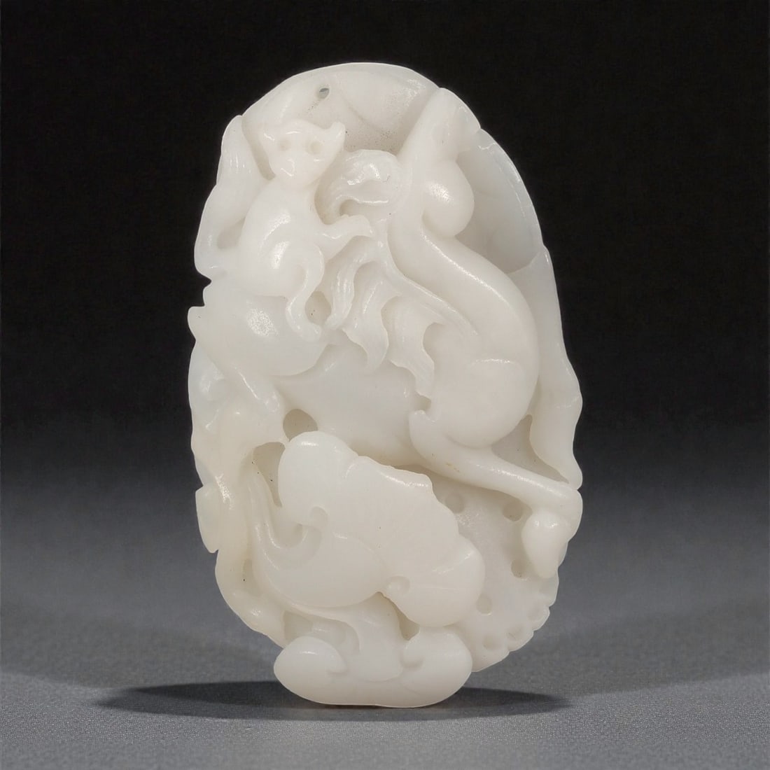 A Chinese Hetian Jade Openwork Carving of a Monkey, 20th Century, 2FD: Carved from pale white Hetian jade with a soft, even translucency, the object is worked as an oval-form openwork carving depicting a monkey shown in a dynamic, climbing posture. The animal is rendered