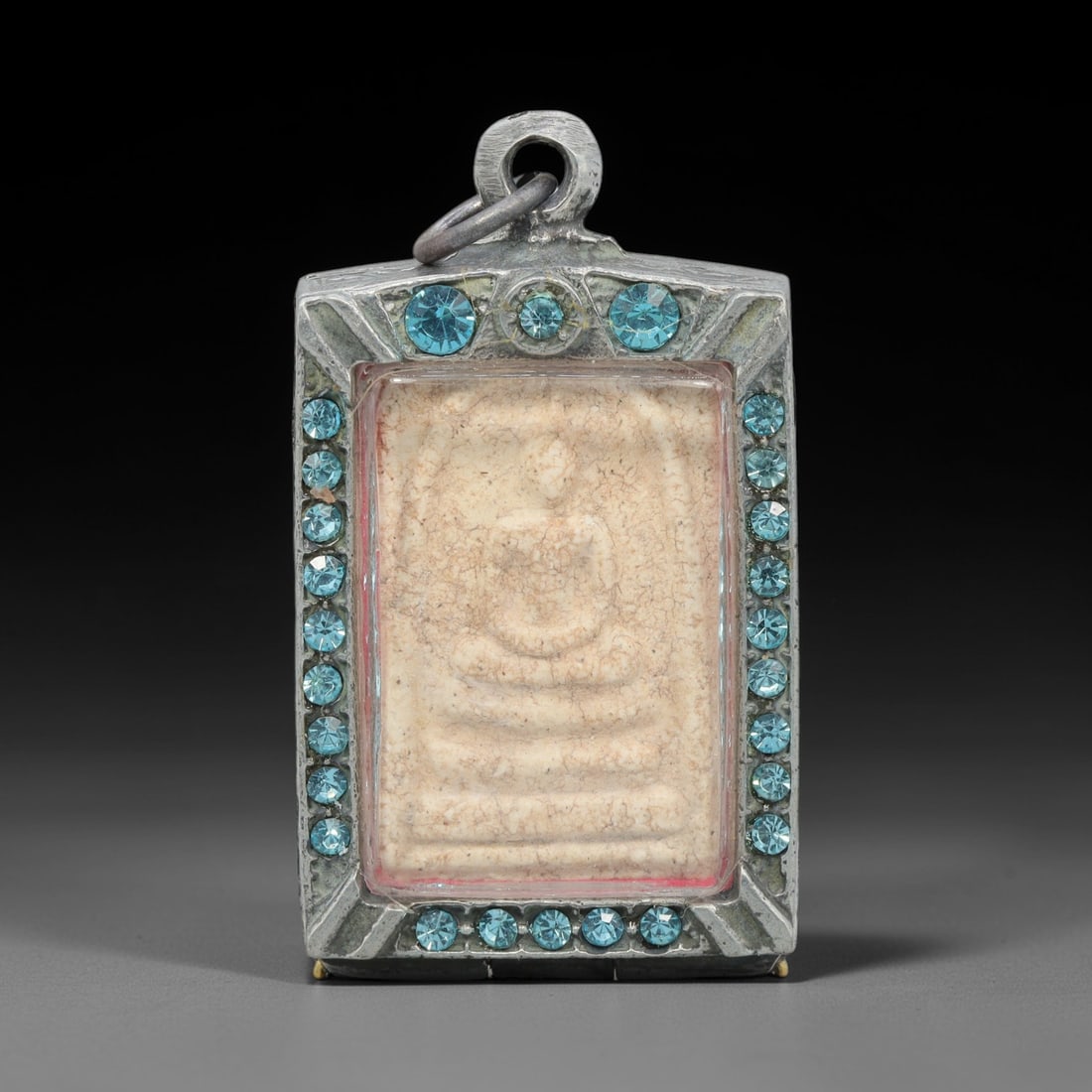 A Thai Phra Somdej Amulet in Metal Case, Late 20th Century, 59ZH: A rectangular amulet, measuring 6 x 3.3 cm, housed in a hinged metal case. The obverse of the case displays the iconic Phra Somdej Buddha figure in seated meditative posture on a multi-tiered lotus pe