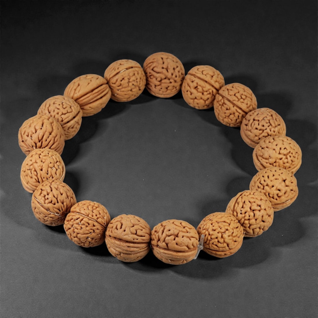A Seed Bead Bracelet, 20th-21st Century, 79YB: Composed of a continuous strand of carved natural seeds, drilled and strung to form a circular bracelet. Each bead is rounded to slightly faceted in form and displays dense natural fissures, lobes, an