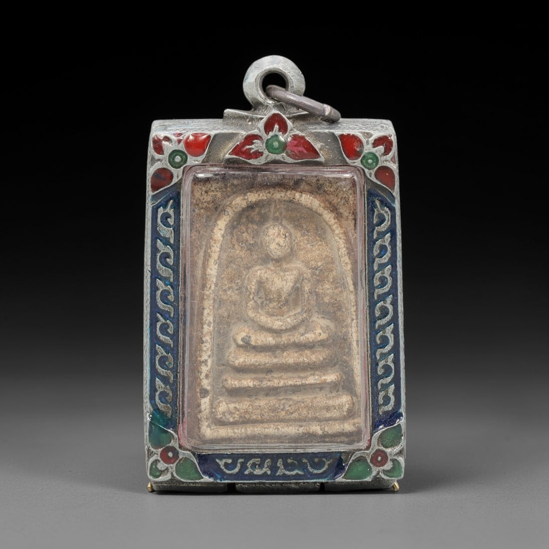 A Thai Terracotta Buddha Amulet in Metal Case, 20th Century, 60ZH: The amulet is formed from terracotta, with a light beige matrix showing surface discoloration and particulate inclusions. The obverse depicts a seated Buddha in meditative posture, seated on a multi-t