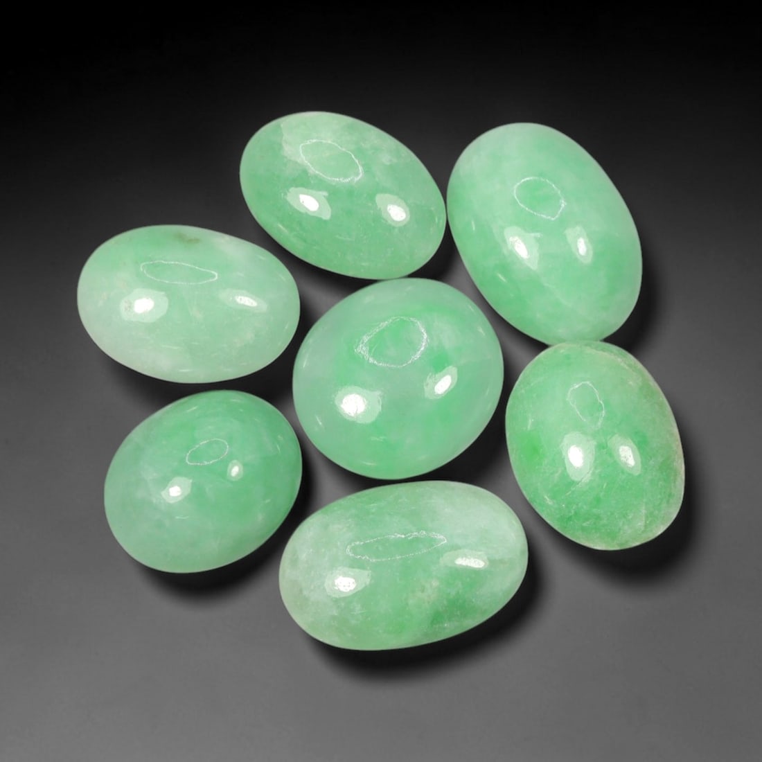 Natural Type A Jadeite Jade - Loose Cabochon Gemstone, 100AN: Crafted from natural Type A jadeite jade, these seven cabochons exhibit a translucent pale green hue with subtle tonal variations inherent to the material. Each stone is cut en cabochon with a smooth,