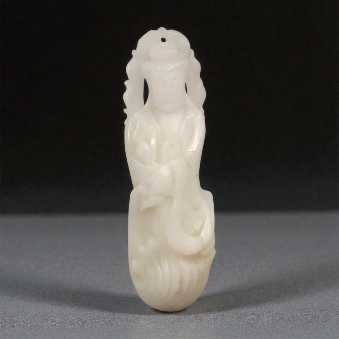 A Chinese Hetian Jade Guanyin Figure, 20th Century, 16FC: Carved from pale white Hetian jade with a softly translucent body and minor natural inclusions, the figure is worked in the round as Guanyin shown standing in a frontal pose. The bodhisattva is depict