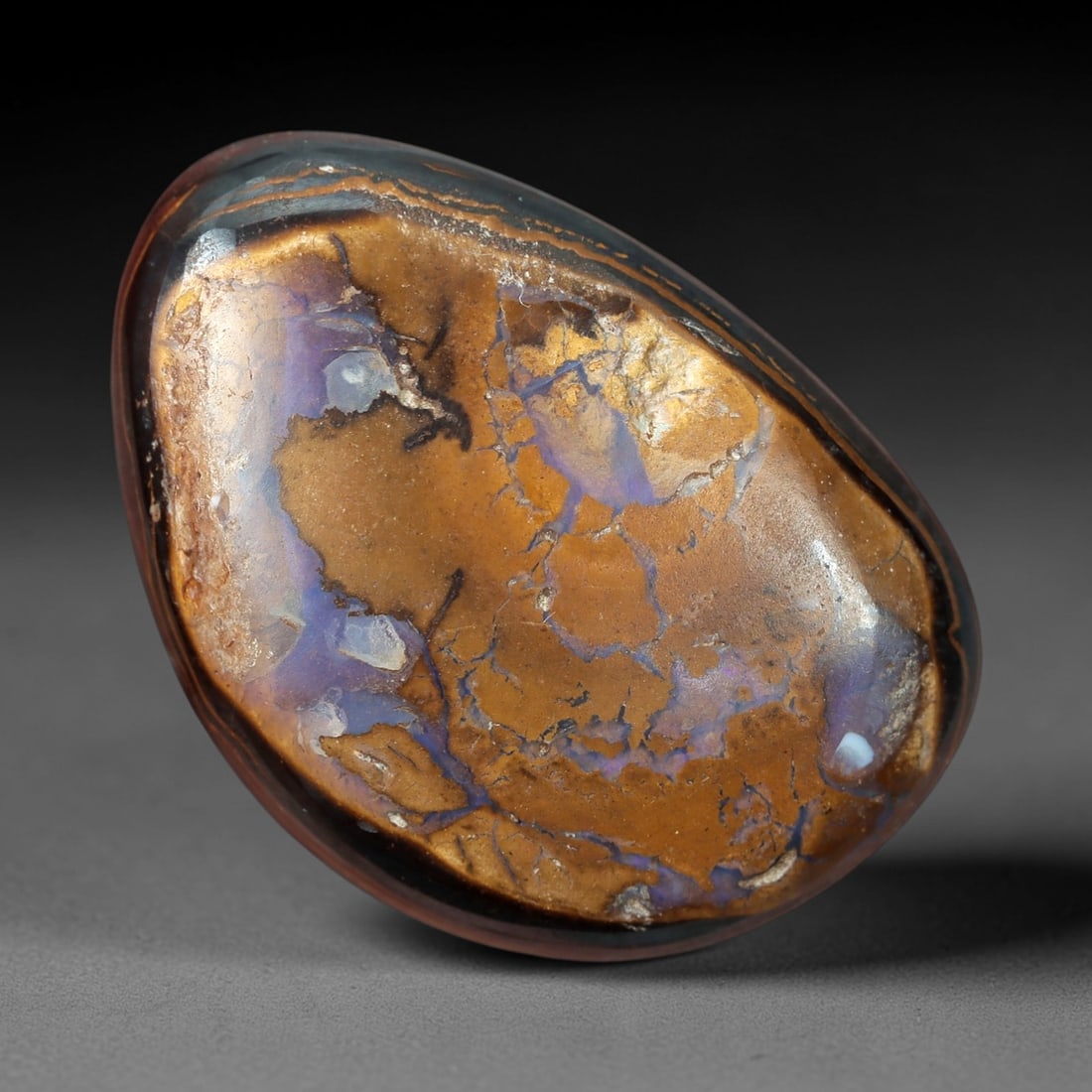10.56 Carats Brown Matrix and Violet Vein Yowah Opal Cabochon - Natural Australian Stone, 45XM: This striking Yowah opal cabochon features a smooth, oval form with a rich brown ironstone matrix crisscrossed by delicate, iridescent violet veins of opal. The stone's polished surface enhances the c