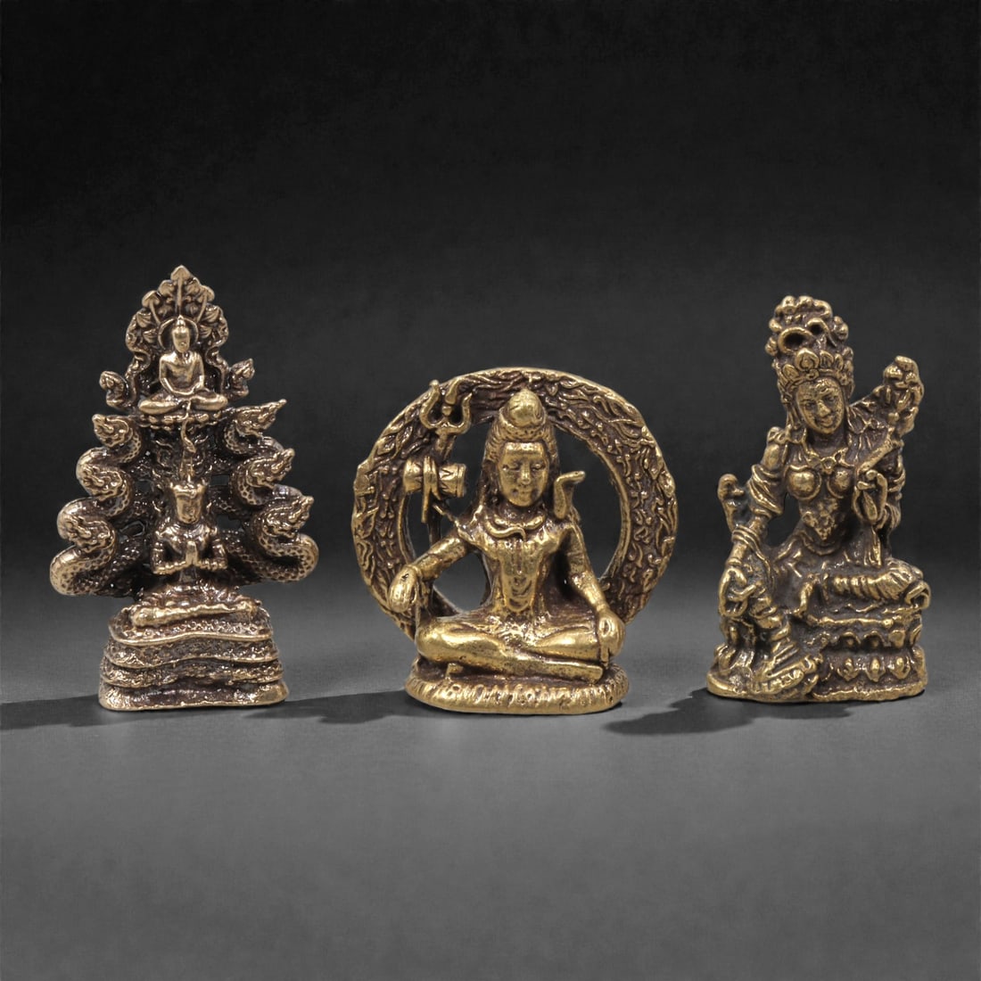 A Group of Thai Copper Alloy Religious Figures, 20th Century, 10ZG: Cast in copper alloy with gilt-toned surfaces and areas of darker patination, the group comprises three small-scale religious figures associated with Thai Buddhist and syncretic Hindu traditions. One