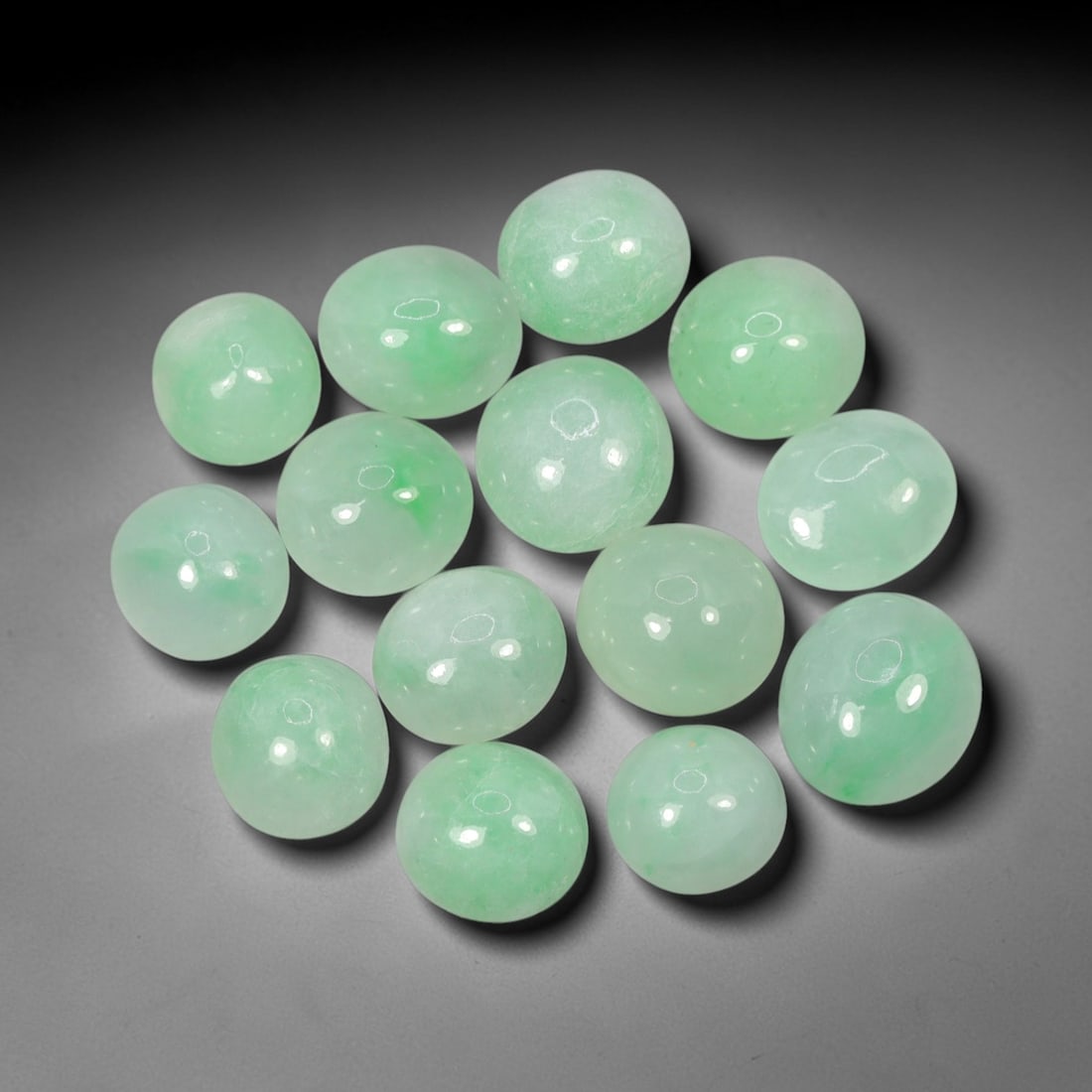 Natural Type A Jadeite Jade - Loose Cabochon Gemstone, 96AN: Crafted from natural Type A jadeite jade, these fourteen cabochons display a translucent pale green hue with subtle tonal variations inherent to the material. Each stone is cut en cabochon with a smoo