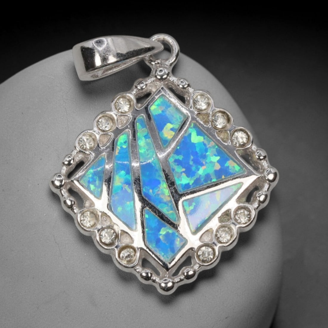 4.87g 925 Sterling Silver Diamond Pendant - Simulated Opal, 18D: Crafted from stamped 925 sterling silver, this pendant features a geometric diamond-shaped frame with polished openwork detailing. The central area is inlaid with irregular segments of simulated opal,