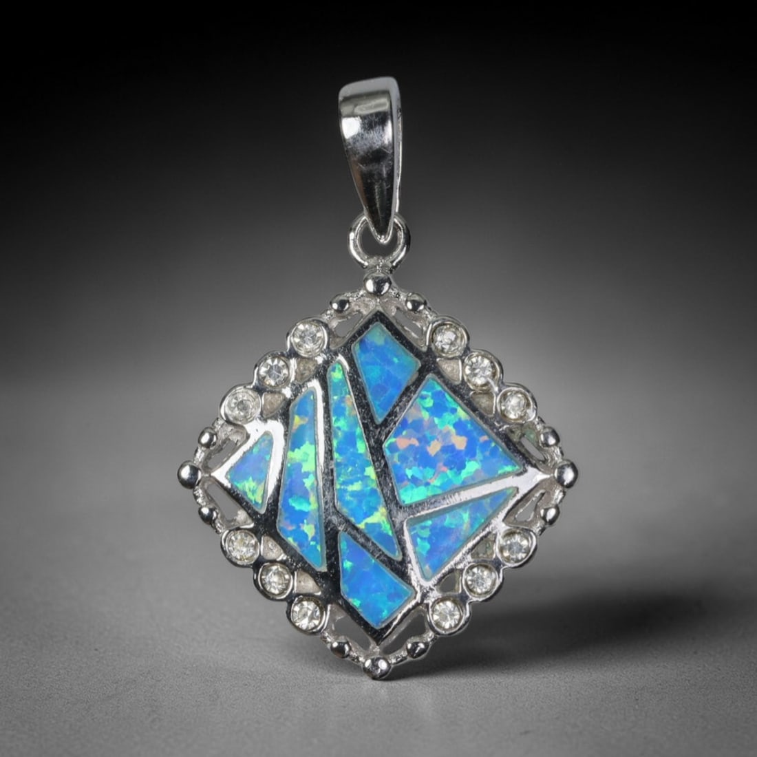 4.94g 925 Sterling Silver Diamond Pendant - Simulated Opal, 12D: Crafted from stamped 925 sterling silver, this pendant features a geometric diamond-shaped frame with polished openwork detailing. The central area is inlaid with irregular segments of simulated opal,