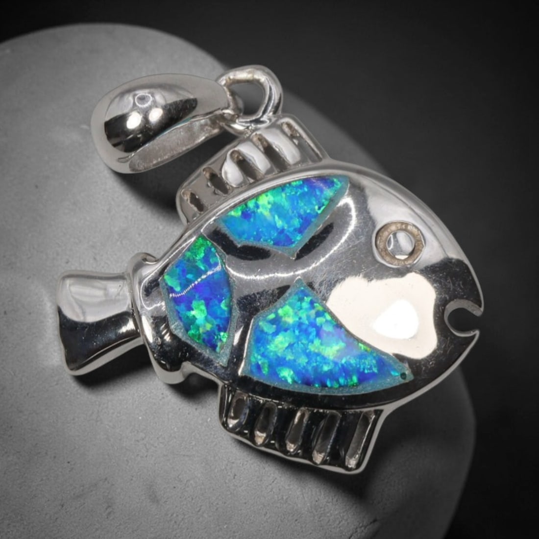 3.35g 925 Sterling Silver Fish Pendant - Simulated Opal, 21D: Crafted from stamped 925 sterling silver, this pendant depicts a stylized tropical fish in polished finish. The fish's body is inlaid with three segments of vibrant simulated opal, displaying vivid ir