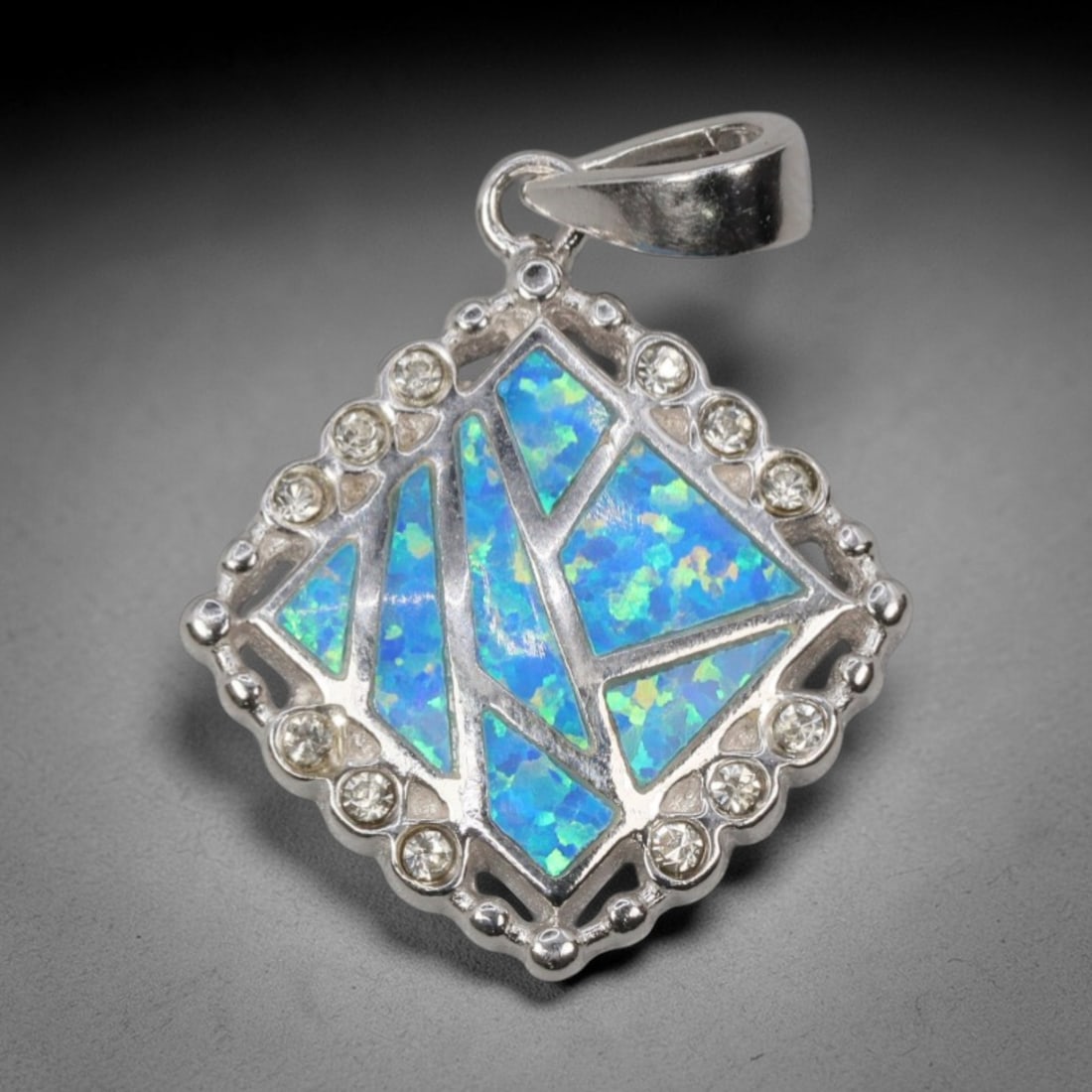 4.81g 925 Sterling Silver Pendant - Simulated Opal Diamond Accent, 2D: Crafted from stamped 925 sterling silver, this pendant features a geometric diamond-shaped frame with polished openwork detailing. The central area is inlaid with irregular segments of simulated opal,
