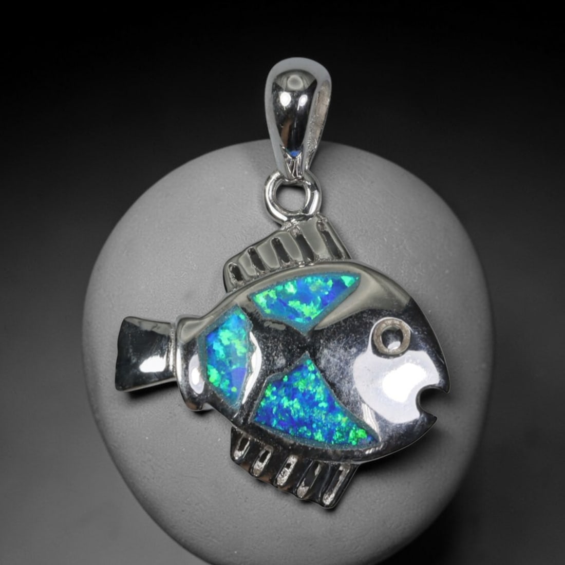 3.28g 925 Sterling Silver Fish Pendant - Simulated Opal, 22D: Crafted from stamped 925 sterling silver, this pendant depicts a stylized tropical fish in polished openwork form. The fish's body is inlaid with three segments of simulated opal, exhibiting vivid iri