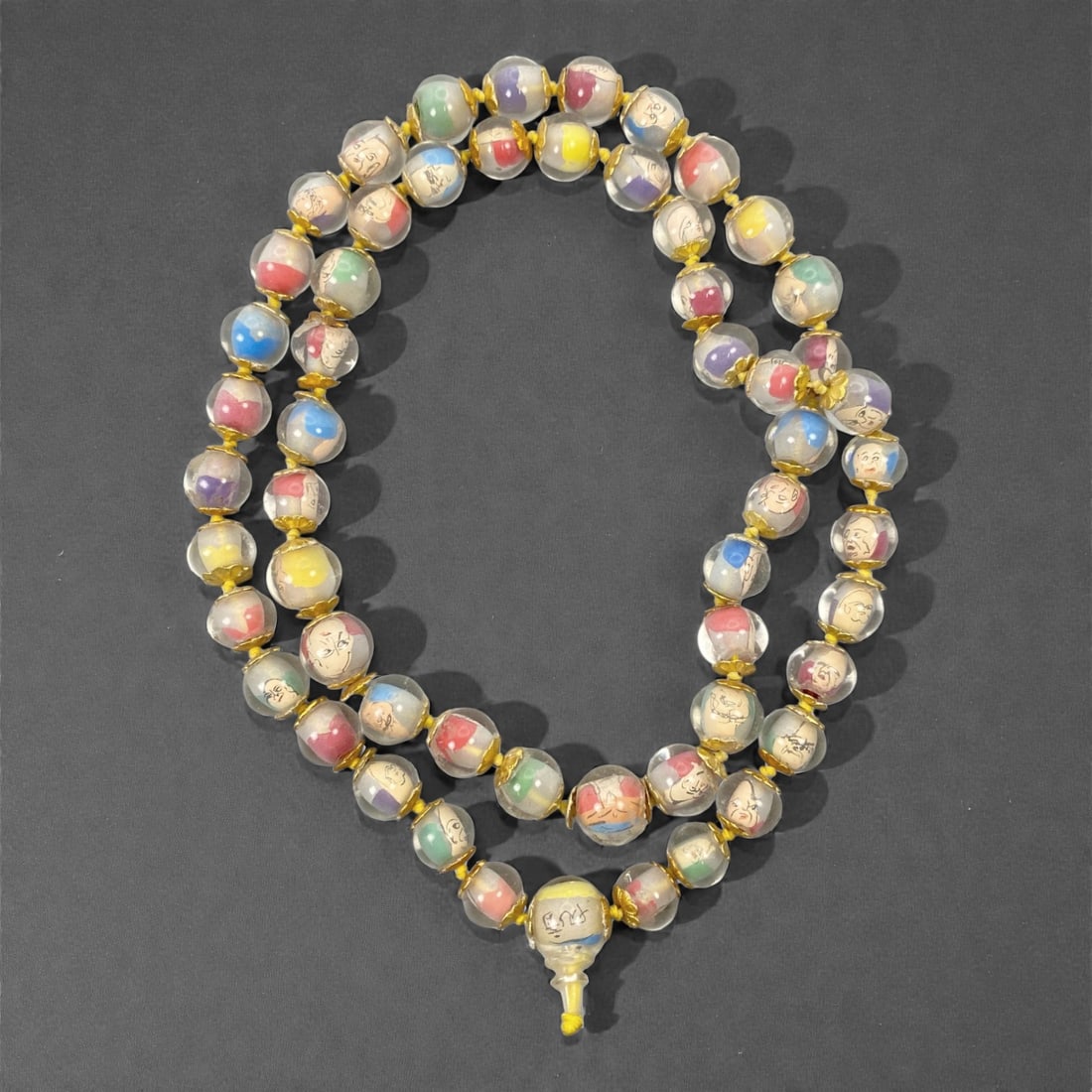 A Chinese Glass Beaded Necklace with Inner Painting, 20th Century, 38FJ: The necklace is composed of a long strand of spherical transparent glass beads, each finely decorated with inner-painted figural portraits rendered in black line against softly colored grounds of red,