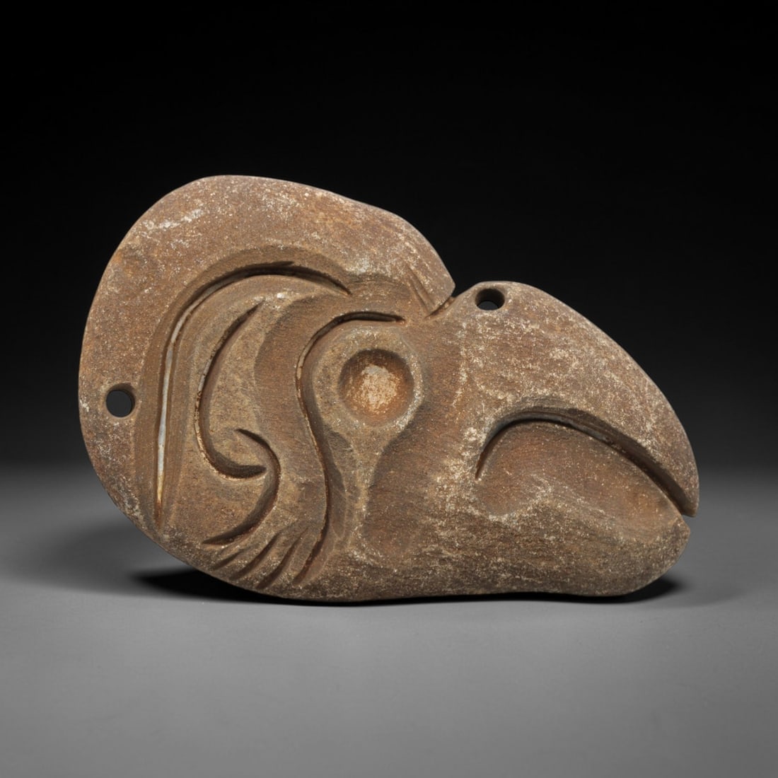 Ancient Stone Bird Amulet - Near Eastern Carving, 71ZV: This artifact is a carved stone amulet of avian form, executed in a granular, earth-toned stone consistent with ancient Near Eastern lithic traditions. The relief carving depicts a stylized bird head