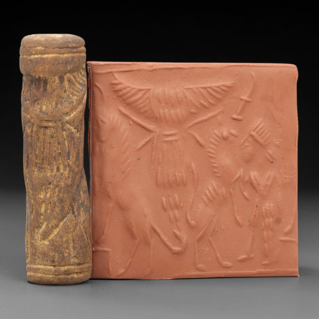 Ancient Steatite Cylinder Seal - Mesopotamian Winged Deity Scene, 94ZR: Carved from dense steatite, this ancient Mesopotamian cylinder seal features a detailed relief composition centered on a prominent winged deity, flanked by animal and human figures in a ritual narrati