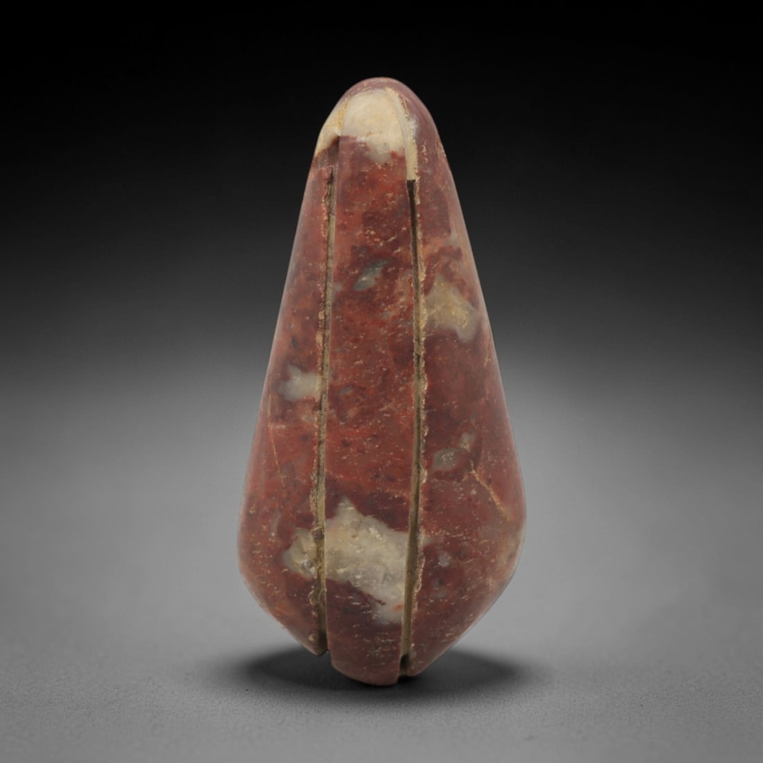 Ancient Stone Bud Amulet - Egyptian Ritual Pendant, 65XQ: Carved from a variegated reddish-brown stone with pale inclusions, this amulet takes the form of a stylized closed bud, tapering to a rounded apex and terminating in a small indented base. Two paralle