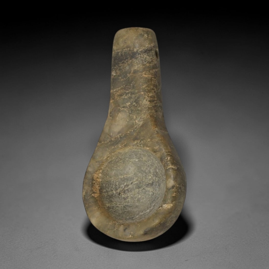 Ancient Green Stone Amulet - Near Eastern Spoon-Form Pendant, 83XP: Carved from a mottled green stone, this amulet features a distinct spoon-shaped form with a narrow, perforated stem and a rounded, concave bowl, designed for suspension as a wearable ritual relic. The