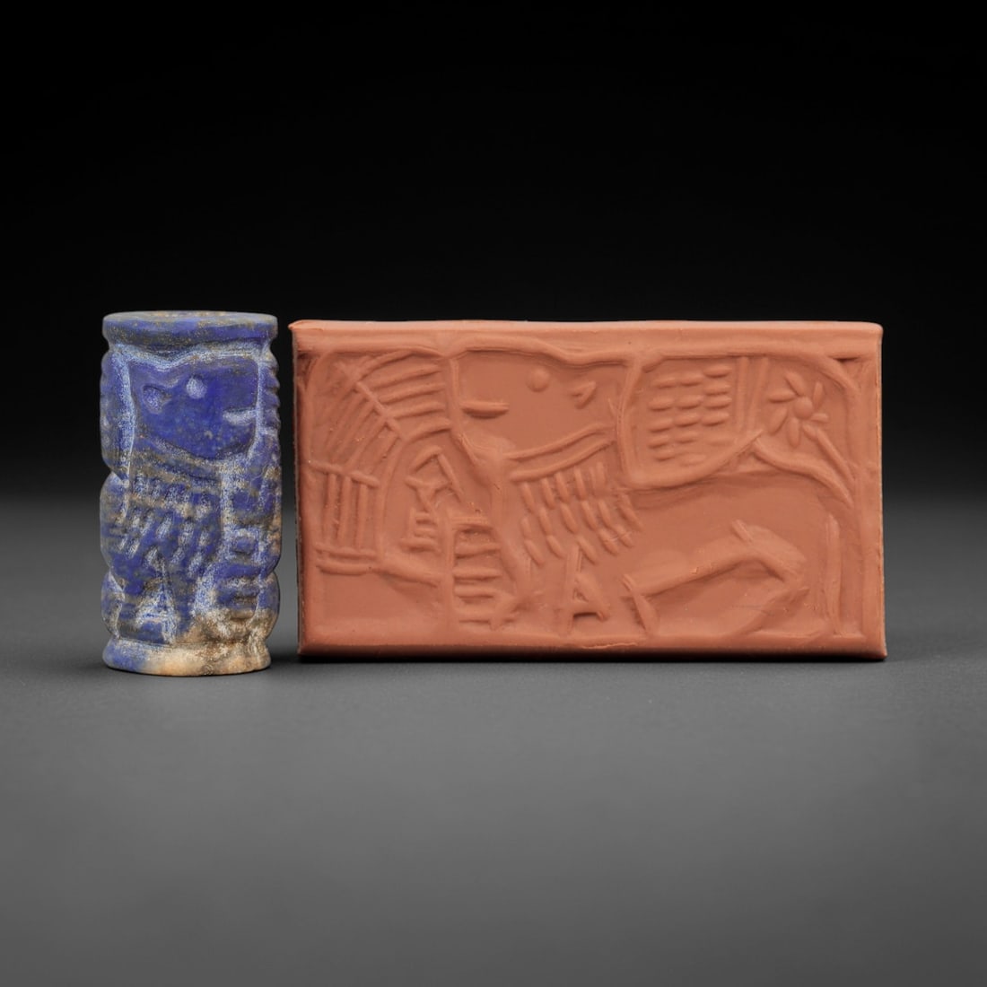 Ancient Near Eastern Lapis Lazuli Cylinder Seal - Lion & Architectural Motif, 66AH: Carved from lapis lazuli, this cylinder seal features incised depictions of a lion figure alongside architectural elements, a motif characteristic of ancient Near Eastern glyptic art. The piece exhibi