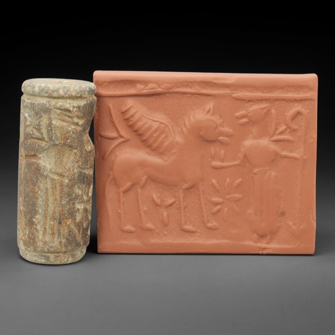 Ancient Steatite Cylinder Seal - Near Eastern Glyptic Art, 80ZQ: Carved from steatite, this ancient Near Eastern cylinder seal features an intaglio scene depicting a winged equine figure flanked by humanoid attendants and radiating motifs, characteristic of Mesopot