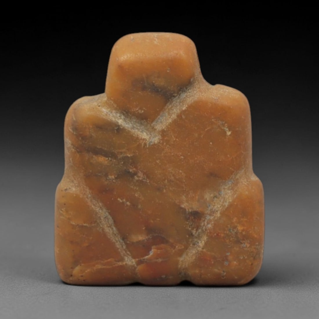 Ancient Stone Anthropomorphic Idol - Near Eastern Figurine, 49XQ: Carved from a warm orange-brown stone with natural veining, this idol depicts a highly stylized, abstract seated anthropomorphic form with a rounded head, broad shoulders, and a compact, stable base.