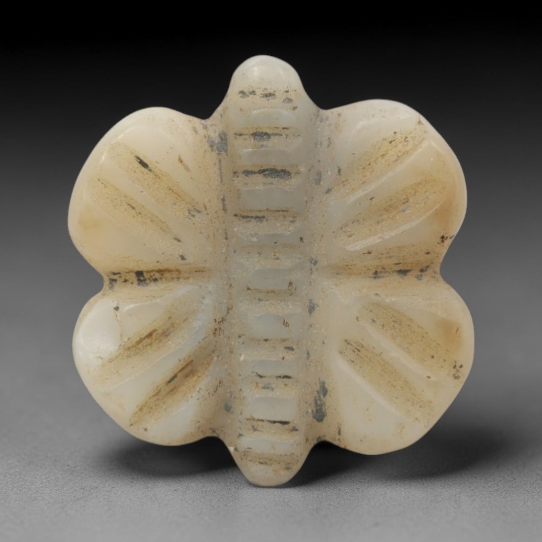 Ancient Near Eastern White Stone Butterfly Amulet - Carved Pendant Figure, 92ZW: This amulet is carved from a pale, creamy white stone, likely calcite or travertine, with incised linear details defining its stylized butterfly form. The piece features a symmetrical four-winged silh