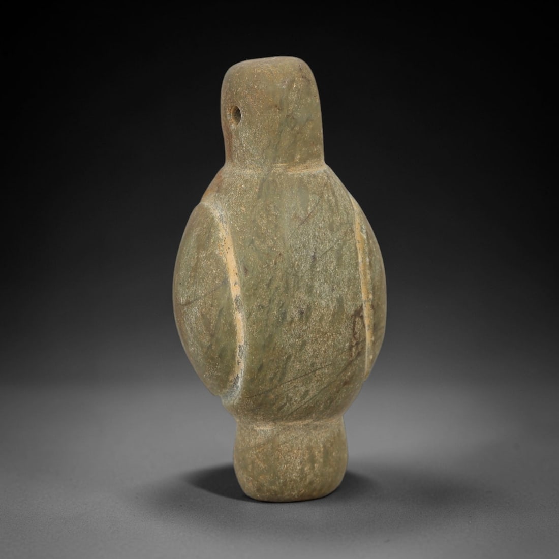 Ancient Stone Bird Amulet - Egyptian Ritual Figurine, 63AE: This amulet is carved from a single piece of grey-green stone, exhibiting a fine, compacted texture with subtle linear veining across the surface. The form is schematically rendered as a bird, with a