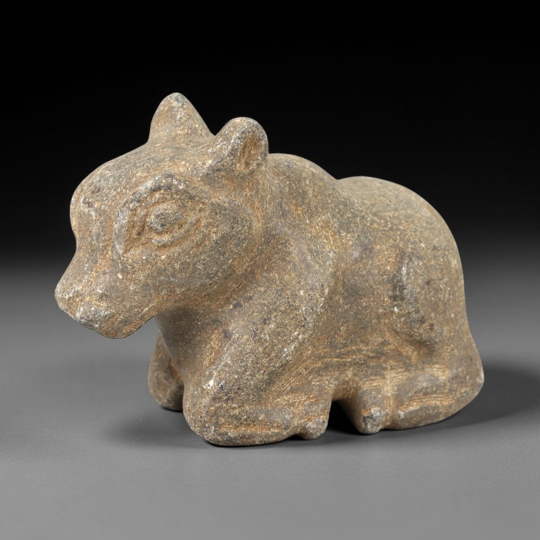 Ancient Stone Bovine Effigy - Near Eastern Animal Figure, 2AM: This bovine effigy is carved from speckled grey stone, depicting a stylized quadrupedal animal in a crouched posture, with incised linear detailing defining the facial features, ears, and limbs. The p