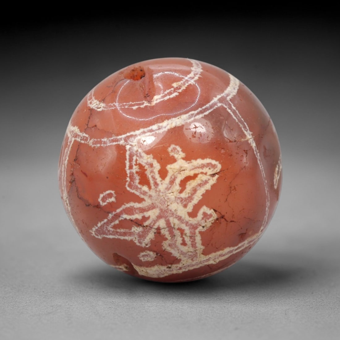 Ancient Carnelian Etched Dzi Bead - Himalayan Amulet, 64XV: Crafted from rich translucent carnelian, this spherical bead features a prominent etched white star-like motif, accompanied by linear band patterns, applied using traditional Himalayan Dzi bead techni
