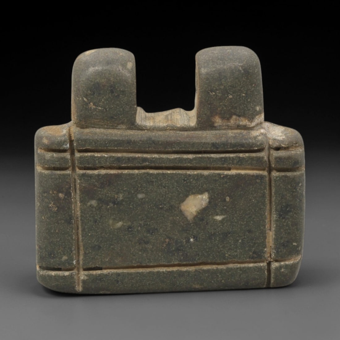 Ancient Stone Amulet - Near Eastern Double Loop Pendant, 37XQ: This amulet is carved from a dense, dark gray stone, featuring a rectangular body with two raised, perforated suspension loops at the upper edge, confirming its use as a wearable protective charm. The