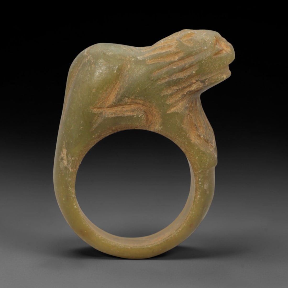 Ancient Serpentine Ring - Achaemenid Carved Signet Ring, 36ZQ: Carved from serpentine, this ancient Achaemenid ring features a stylized animal head motif with linear detailing, characteristic of Achaemenid glyptic art. The ring exhibits a smooth, aged patina cons