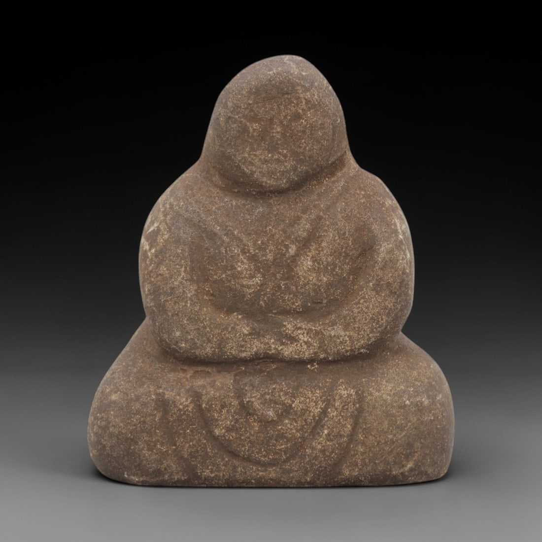 Ancient Stone Monk - Japanese Edo Period Figurine, 30FX: Carved from a coarse, textured stone, this Edo period figure depicts a monk in a seated, meditative posture with crossed legs, the hands resting in a traditional lap position. The form is simplified a