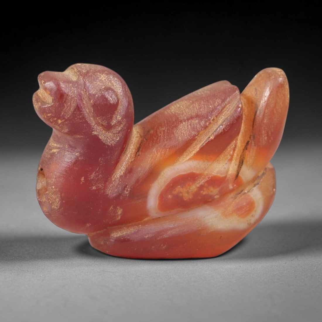 Ancient Carnelian Duck - Near Eastern Zoomorphic Amulet, 23AS: This zoomorphic amulet is carved from banded carnelian, exhibiting a rich reddish-orange hue with distinct white banding and a warm, earthy patina consistent with ancient Near Eastern burial contexts.