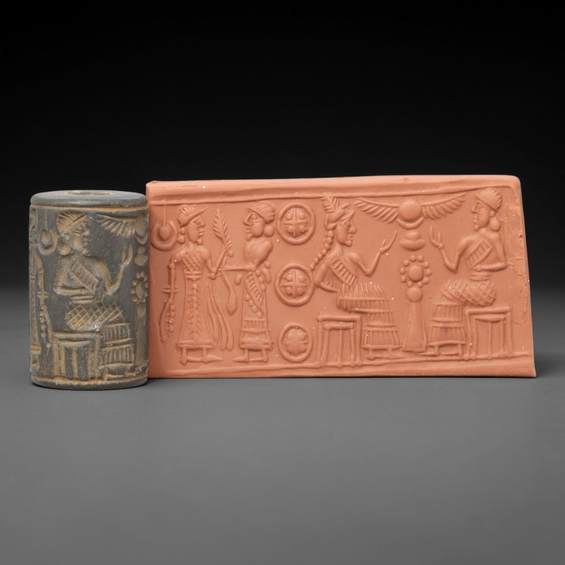 Ancient Steatite Cylinder Seal - Mesopotamian Royal Audience & Winged Sun Disk Scene, 22ZP: Carved from dark, weathered steatite, this ancient Mesopotamian cylinder seal depicts a formal royal audience scene, executed with precise glyptic craftsmanship characteristic of the Neo-Assyrian peri
